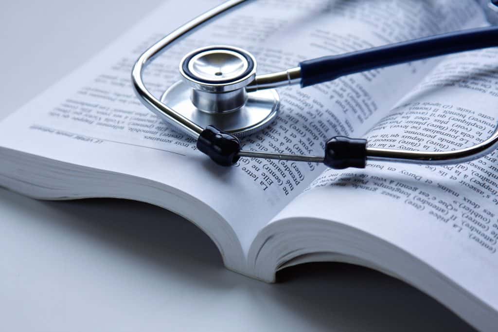 A stethoscope is lying on an open book